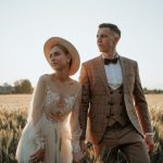 Romantic wedding portrait of a couple posing in a sunlit field, highlighting elegance and love.